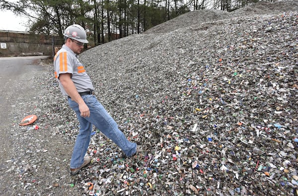 Tom Fletcher, plant manger, shows mixed recyclable materials at Strategic Materials recycling facility in College Park. (HYOSUB SHIN / HSHIN@AJC.COM)