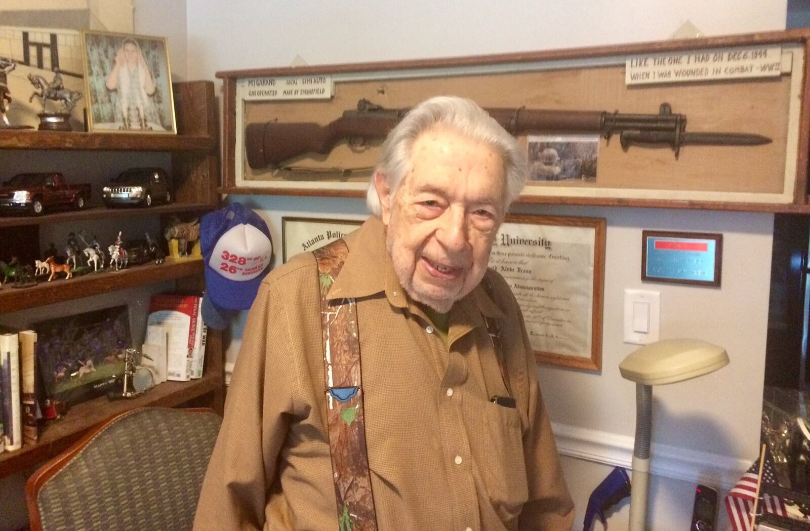 Harold Vrono, 95, in his apartment in Sandy Springs. Behind him is a rifle similar to the one he carried in Europe in World War II. On another wall is his Purple Heart. Photo by Bill Torpy.