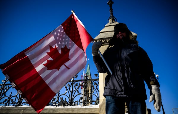 A protester held a flag of Canada and the United States on Parliament Hill in Ottawa on Saturday.