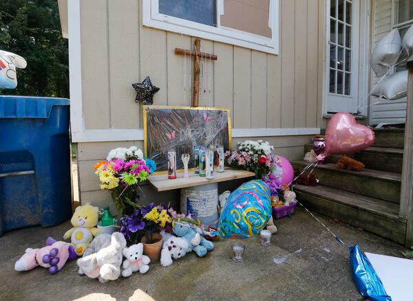 Flowers and stuffed toys left on the doorstep of a home where four children and their father were stabbed to death are shown Friday, July 7, 2017, in Loganville , Ga. Isabel Martinez the children's mother and the man's wife has been charged with the crimes. (AP Photo/John Bazemore)