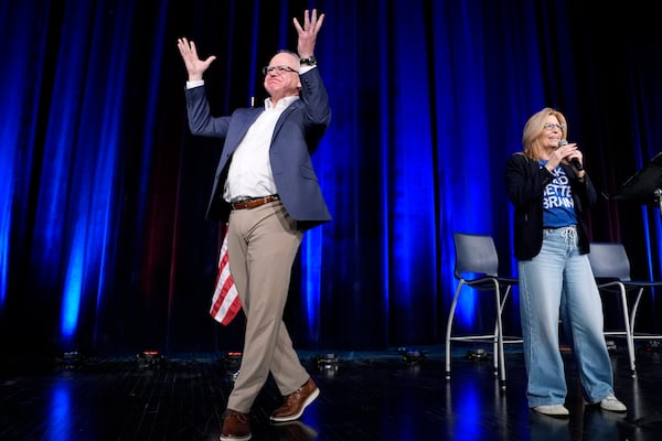 Minnesota Gov. Tim Walz, left, is introduced onstage by Rita Hart, chair of the Iowa Democratic speak at a town hall event at Roosevelt High School, Friday, March 14, 2025, in Des Moines, Iowa. (AP Photo/Matthew Putney)