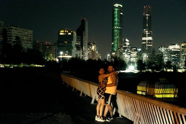 A couple embraces on a street during a power outage in Santiago, Chile, Tuesday, Feb. 25, 2025. (AP Photo/Matias Basualdo)