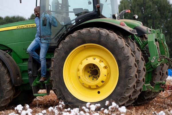 Sen. Rev. Raphael Warnock slips out of the tractor cab after taking a ride with Lee Nunn during a tour of his farm in Madison on Wednesday, Oct. 11, 2023.ÊÊÊ(Ben Gray / Ben@BenGray.com)