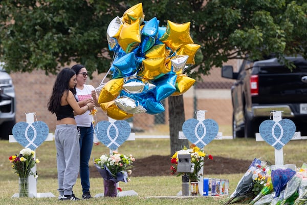 Mourners visit crosses erected at Apalachee High School on Friday, Sept. 6, 2024, in Winder, Ga. A 14-year-old Apalachee student is accused of shooting and killing two fellow students and two teachers and injuring nine others at Apalachee High School on Wednesday. (Arvin Temkar / AJC)