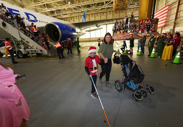 Nine-year-old Rylan Hadad, left, walks with his mother, Eva, during the United Airlines annual "fantasy flight" to a fictional North Pole at Denver International Airport, Saturday, Dec. 14, 2024, in Denver. (AP Photo/David Zalubowski)