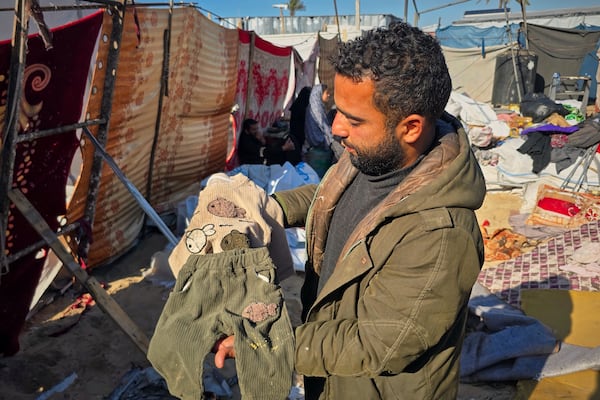 Alaa Abu Helal shows the clothes of his 13-month-old son, Mohammed, before Mohammed and his pregnant mother, Afana, are buried in Khan Younis, Gaza Strip, Wednesday, March 19, 2025. They were killed before dawn on Tuesday by an Israeli airstrike. (AP Photo/Mohammad Jahjouh)