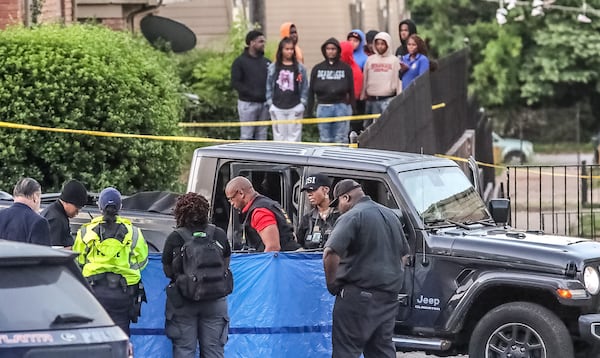 Investigators covered a body lying outside a gray Jeep Gladiator with a blue tarp.