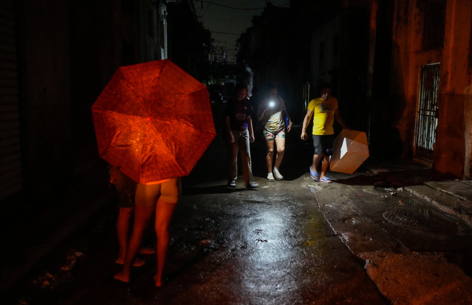 Residents walk down a street using a phone flashlight during a power outage following the failure of a major power plant in Havana, Cuba, Saturday, Oct. 19, 2024. (AP Photo/Ramon Espinosa)