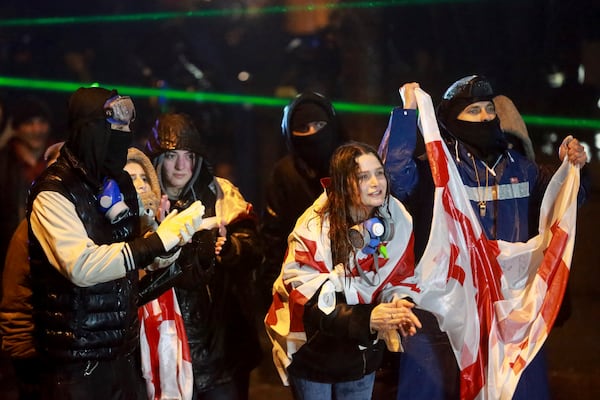 Protesters with Georgian national flags shout toward police during a rally against the governments' decision to suspend negotiations on joining the European Union for four years, outside the parliament's building in Tbilisi, Georgia, on Sunday, Dec. 1, 2024. (AP Photo/Zurab Tsertsvadze)