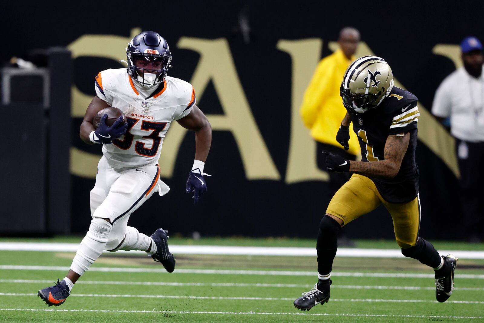 Denver Broncos running back Javonte Williams (33) runs from New Orleans Saints cornerback Alontae Taylor (1) during the second half of an NFL football game, Thursday, Oct. 17, 2024, in New Orleans. (AP Photo/Butch Dill)