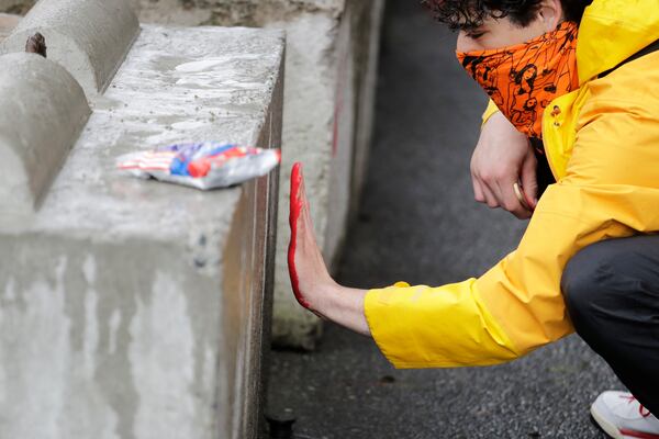 A man leaves a red paint handprint on a barricade near a closed Seattle police precinct.