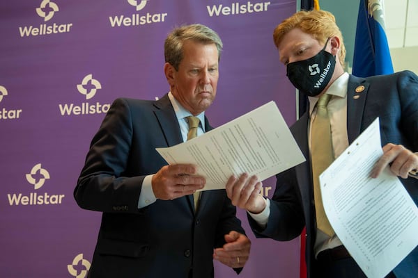 Gov. Brian Kemp’s intervention in the hospital fight is another sign of his behind-the-scenes strategy so far this legislative session.  In this 2020 photo, he is given a bill to sign following a ribbon cutting ceremony at the new Wellstar Kennestone Hospital Emergency Department building in Marietta. (Alyssa Pointer/The Atlanta Journal-Constitution)