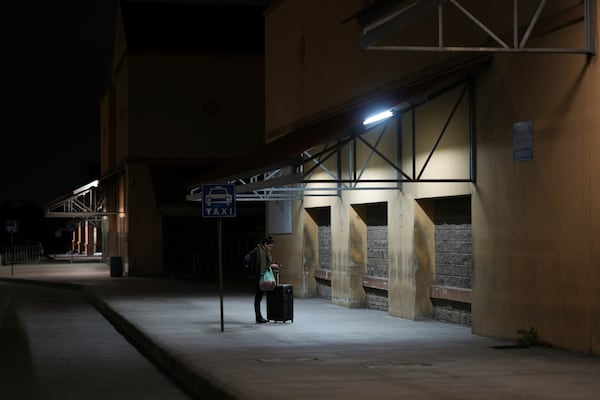 A woman waits for a bus at a station in San Pedro Sula, Honduras, Tuesday, Dec. 3, 2024. (AP Photo/Moises Castillo)