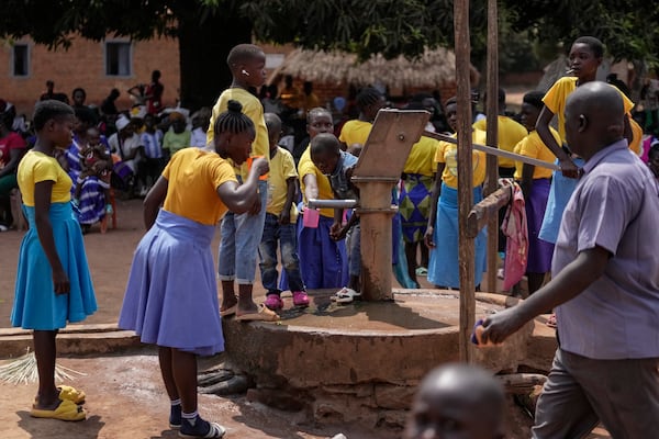 Children drink water from a well near Nzara, South Sudan on Sunday, Feb. 16, 2025. (AP Photo/Brian Inganga)