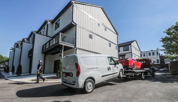 Police tow a white work van and a red Chevrolet Camaro from the One Riverside West community after a deadly shooting Thursday.