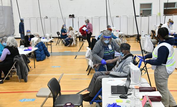 Registered Nurse Kathy Martin, center, prepares to administer a COVID-19 vaccine to Arthur Smith at the Phoebe Healthworks building in Albany in early February. (Hyosub Shin / Hyosub.Shin@ajc.com)