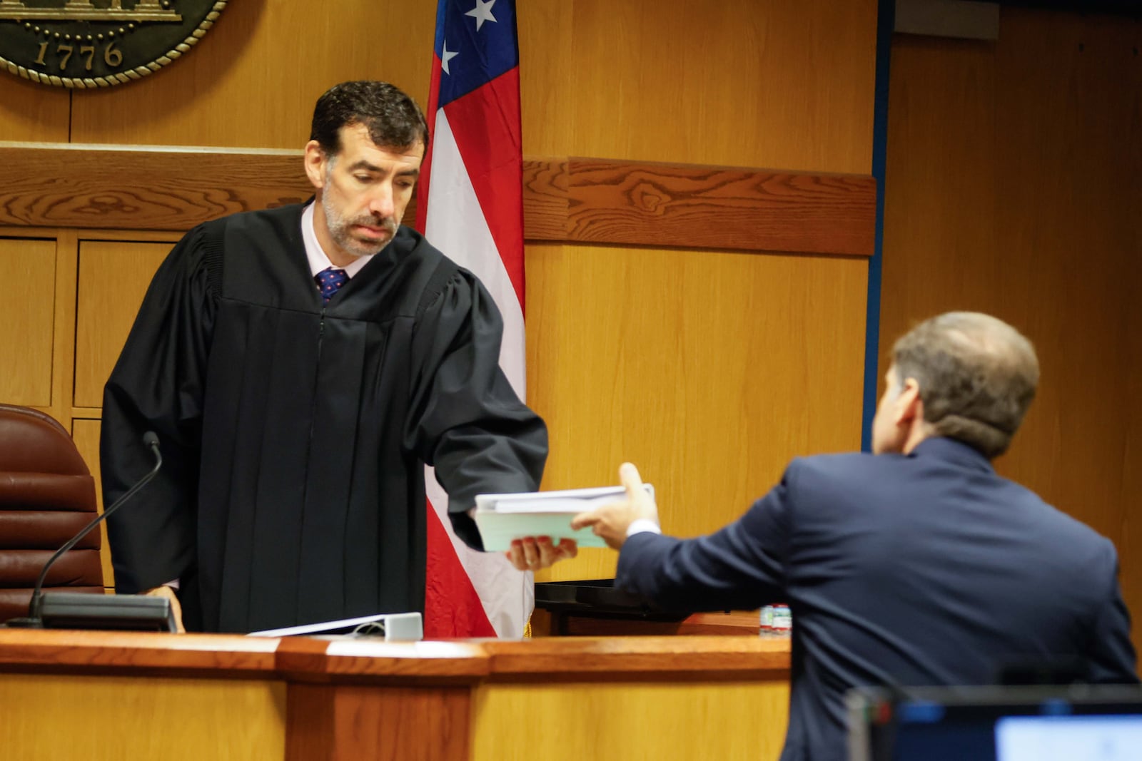 An attorney representing the Cobb County election board, Mike Caplan, hands a document to Fulton County Superior Court Robert McBurney during a hearing Tuesday. (Miguel Martinez / AJC)