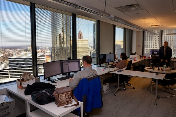 Neighboring buildings are shown in the window as employees with SSOE work in their office space at 100 Peachtree St. on Jan. 13 in Atlanta. The architecture firm has had its offices in downtown for more than 105 years. (Jason Getz / AJC)