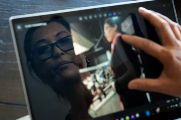 Joy Alessi is reflected in a laptop displaying a photo of her at her naturalization ceremony Monday, June 24, 2024, at home in Henderson, Nev. For most of her life, Alessi was a proud patriot, who got teary-eyed when Garth Brooks sang about America. But patriotism is confusing for her now, as it is for many of the adoptees who've found themselves in this predicament. (AP Photo/David Goldman)