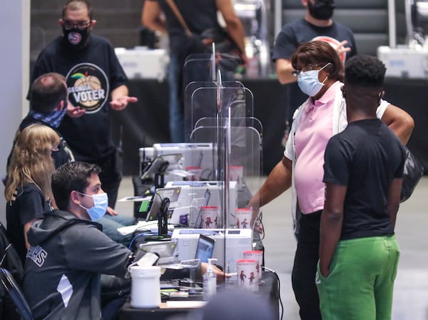 Poll workers check the identity and eligibility of people arriving for early voting on Oct. 12 at State Farm Arena in downtown Atlanta. An investigation by The Atlanta Journal-Constitution shows that Secretary of State Brad Raffensperger’s office weakened Georgia's voting system defenses, disabling password protections on a key component that controls who is allowed to vote. (John Spink / John.Spink@ajc.com)

