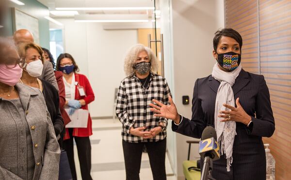 Mayor Keisha Lance Bottoms, right, speaks at Morehouse School of Medicine before her mother, Sylvia Robinson, center, receives the first of two Moderna Covid-19 vaccines Tuesday, January 5, 2021.  Bottoms is waiting to get her vaccine until first responders receive their shots. (Jenni Girtman for The Atlanta Journal-Constitution)