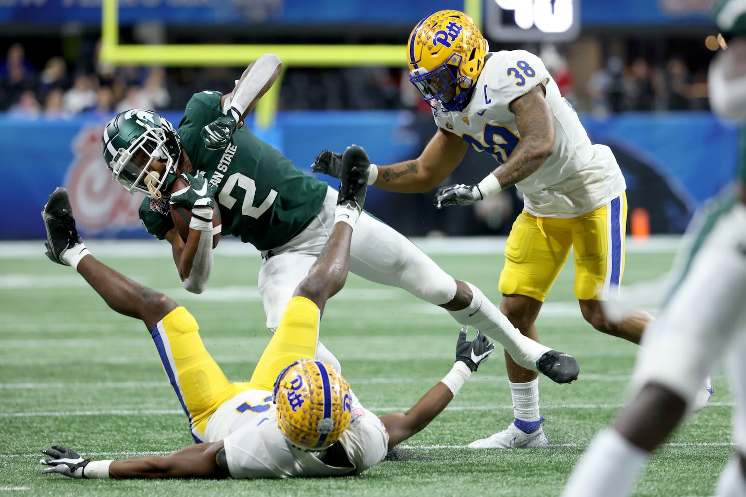 Pittsburgh Panthers linebacker Cam Bright (38, right) and defensive back Erick Hallett (31) tackle Michigan State Spartans running back Harold Joiner (2) after a run during the first half of the Chick-fil-A Peach Bowl at Mercedes-Benz Stadium in Atlanta, Thursday, December 30, 2021. JASON GETZ FOR THE ATLANTA JOURNAL-CONSTITUTION