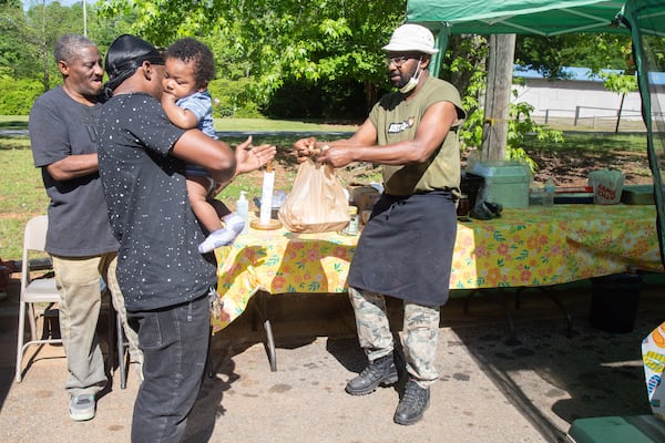 Ashton Morris and his son Ace pick up their barbecue order from Edward Spence at Spence Barbecue along Stone Hogan Connector SW in Atlanta Saturday, April 27, 2019.   STEVE SCHAEFER / SPECIAL TO THE AJC