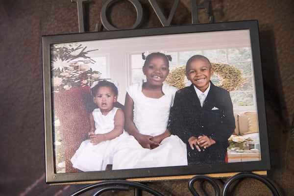 This photo of adopted siblings Karrigan Moses (from left), 2, Ariah Moses, 9, and Kristopher Moses, 8, on display at the family’s residence in Decatur, reflects the happy lives of these children — lives that could have taken another turn if not for the Moses sisters. 