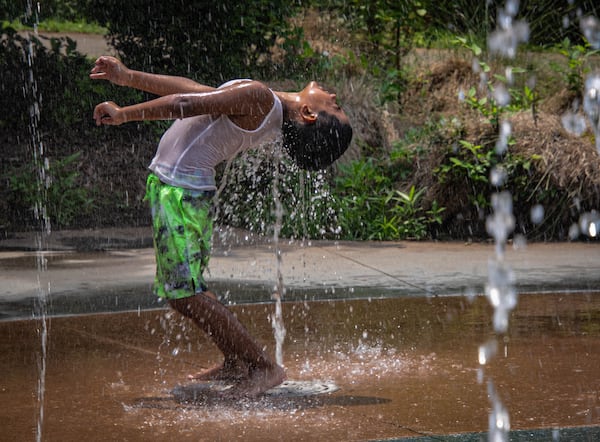 Snyder Acosto-Lopez cools down in the splash pad at Historic Fourth Ward Park in Atlanta. His mother, Belen Lopez has taken her children here often on hot days. (Katelyn Myrick/katelyn.myrick@ajc.com)