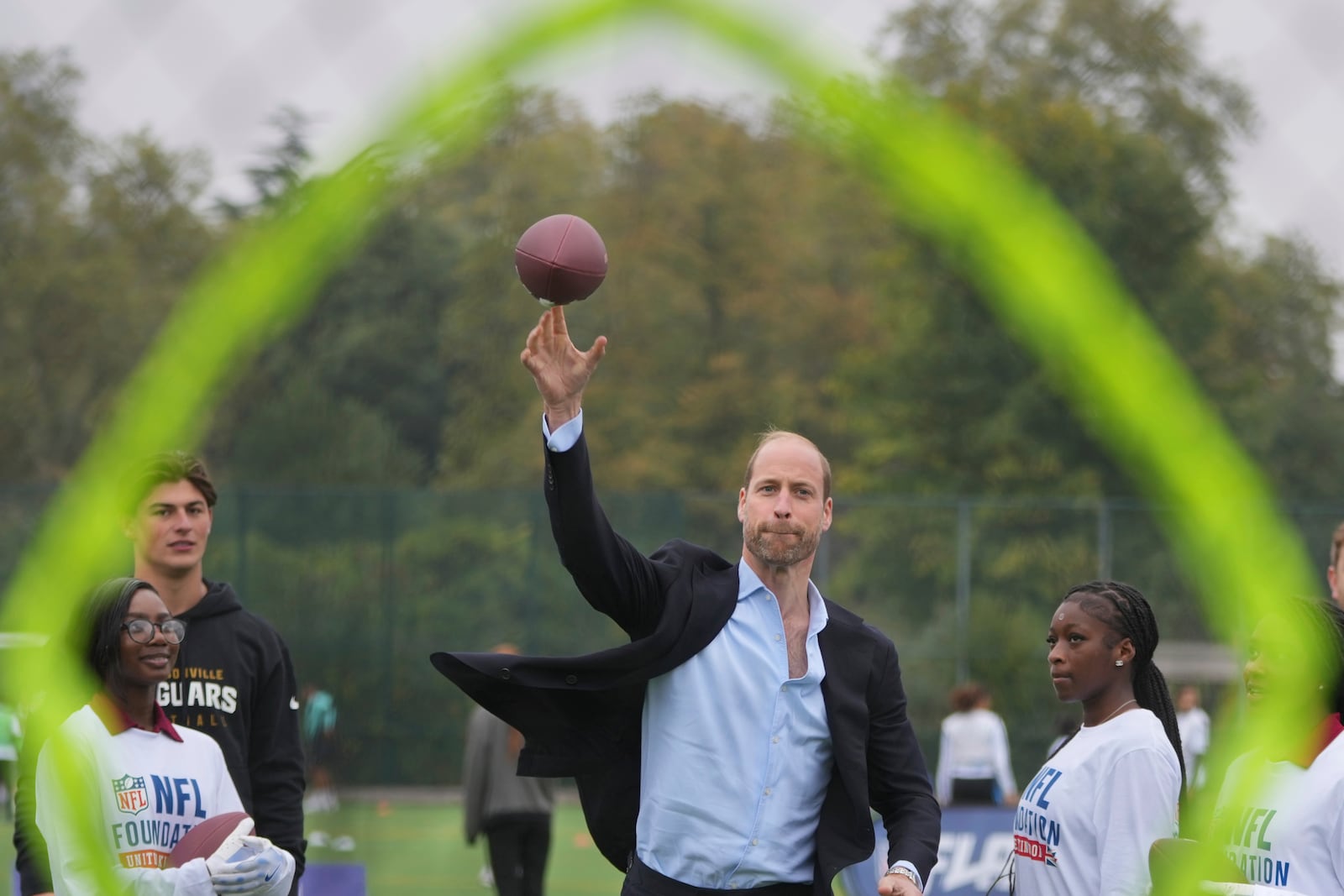 Britain's Prince William throws a football at a target, watched by Louis Rees-Zammit, left, as he attends a NFL Foundation NFL Flag event, an inclusive and fast paced American Football format, in London, Tuesday, Oct. 15, 2024. (AP Photo/Kin Cheung, Pool)