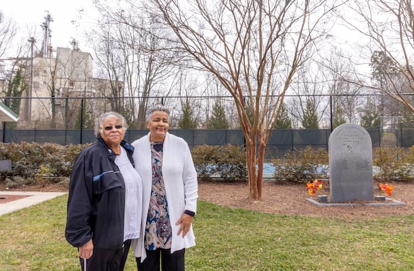 Delinda Luster, left, and Rose Johnson, right, members of the Newtown Florist Club in Gainesville, visit the memorial in place since 1994 to remember residents who have died of cancer or lupus. Members of the community believe that industrial pollution from surrounding areas is linked to death and disease among residents, but no conclusive link has been established. (Jenni Girtman for The Atlanta Journal-Constitution)