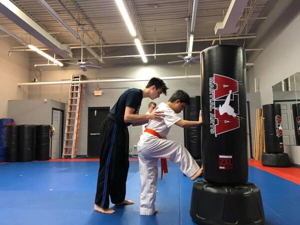 Marcus McAbee (left) helps a student improve his muscle tone so he can kick harder during a recent Friday night class at Karate Atlanta. CONTRIBUTED