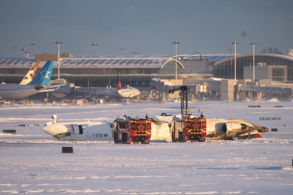 Emergency personnel work at the scene of a Delta Airlines plane crash at Toronto Pearson International Airport on Monday in Toronto. Several passengers were injured on the flight arriving from Minneapolis, resulting in the suspension of all flights at Canada's busiest airport. Katherine KY Cheng/Getty Images/TNS