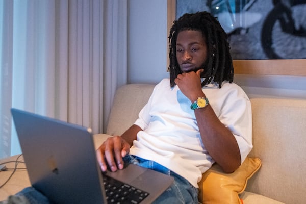 Looking comfortable while concentrating, Justice Baiden, Love Renaissance's head of A&R, works in his Castleberry Hill office. (Ziyu Julian Zhu/AJC)