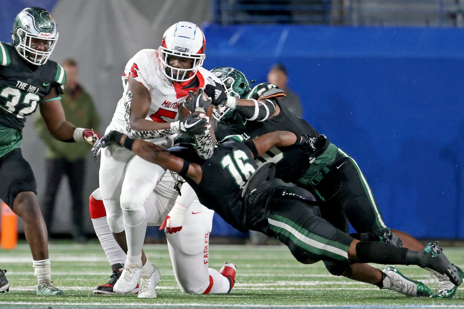 Milton running back Jordan McDonald (5) runs against Collins Hill defenders Cedric Richardson and defensive back Roberto Bryant (16) during the first half of the Class 7A state title football game at Georgia State Center Parc Stadium Saturday, December 11, 2021, Atlanta. JASON GETZ FOR THE ATLANTA JOURNAL-CONSTITUTION