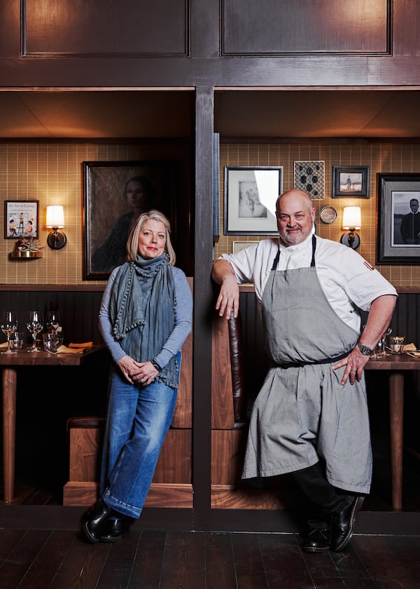 Gina and Chef Linton Hopkins stand in Holeman and Finch in front of a painting of a socialite found in a New York antique shop.  Each of the 9 booths at Holeman and Finch have a curated selection of art that is personal to the Hopkinses. / Courtesy of Holeman & Finch