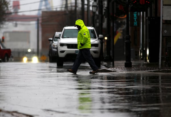 A person walks through the rain as a storm system and possible "bomb cyclone" hit the U.S. East Coast, Wednesday, Dec. 11, 2024 in Portsmouth, N.H. (AP Photo/Caleb Jones)