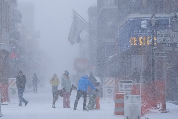 People walk around on Bourbon Street as snow falls in the French Quarter in New Orleans, Tuesday, Jan. 21, 2025. (AP Photo/Gerald Herbert)