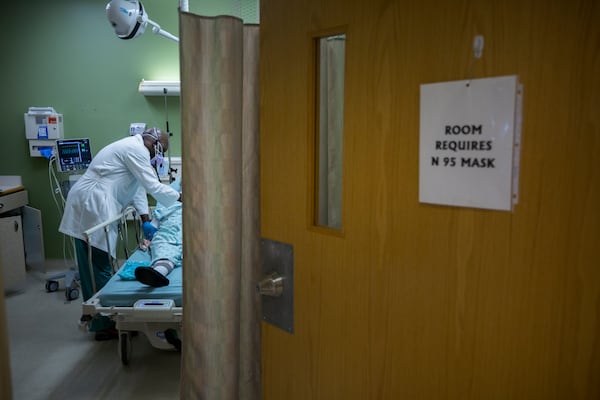 Emergency room physician Dr. Lekan Akinyokunbo, left, checks on a patient diagnosed with Covid-19. (Stephen B. Morton for The Atlanta Journal-Constitution)