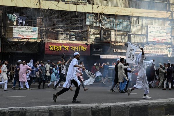 Members and supporters of the banned Islamist group Hizbut Tahrir run after police using tear gas to disperse them near Baitul Mokarram Mosque in Dhaka, Bangladesh, Friday, March 7, 2025. (AP Photo/Mahmud Hossain Opu)