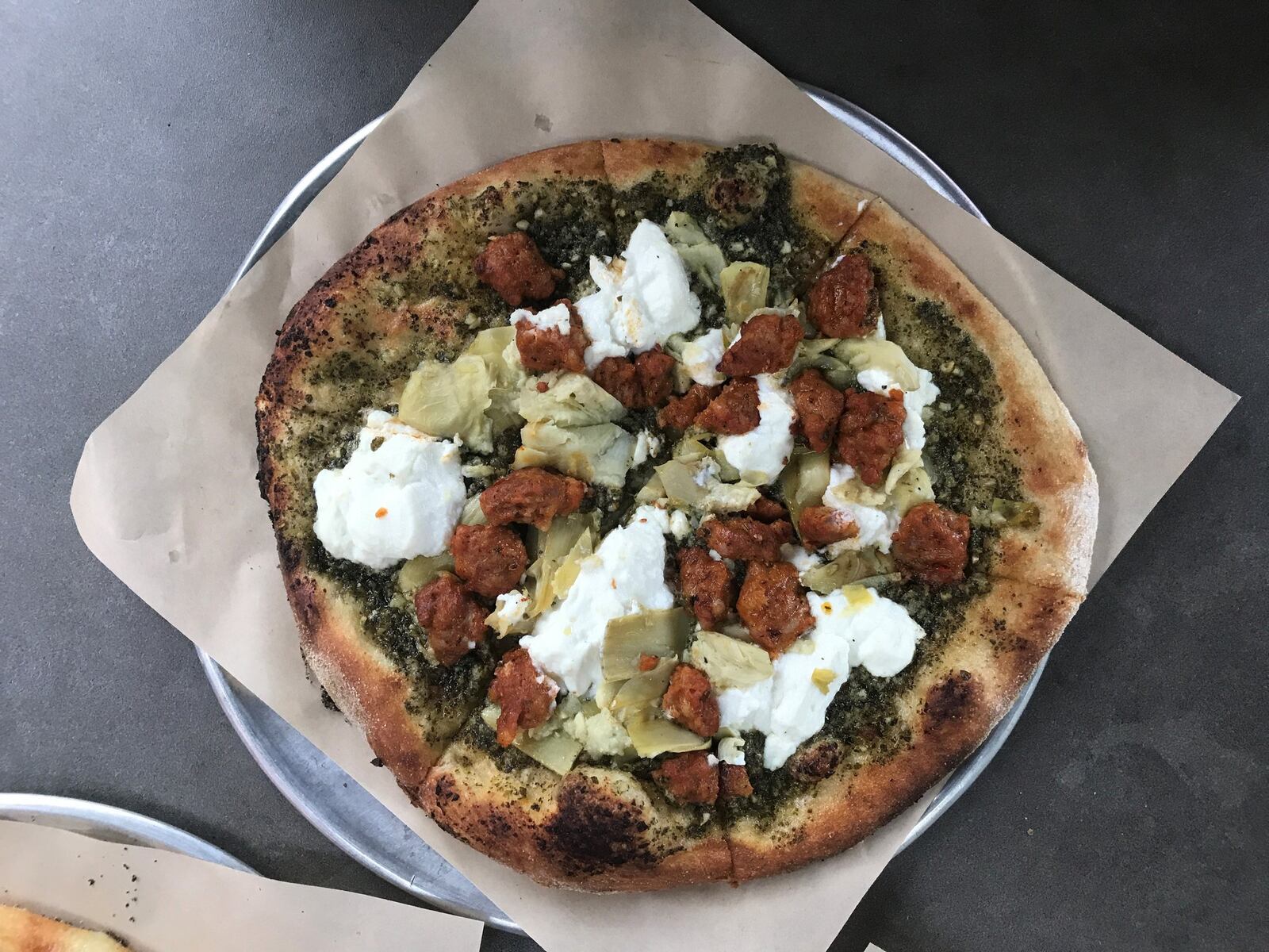 This build-your-own pizza from Your Pie includes basil pesto, ricotta, Italian sausage, artichoke hearts and garlic on a wheat crust. LIGAYA FIGUERAS / LFIGUERAS@AJC.COM