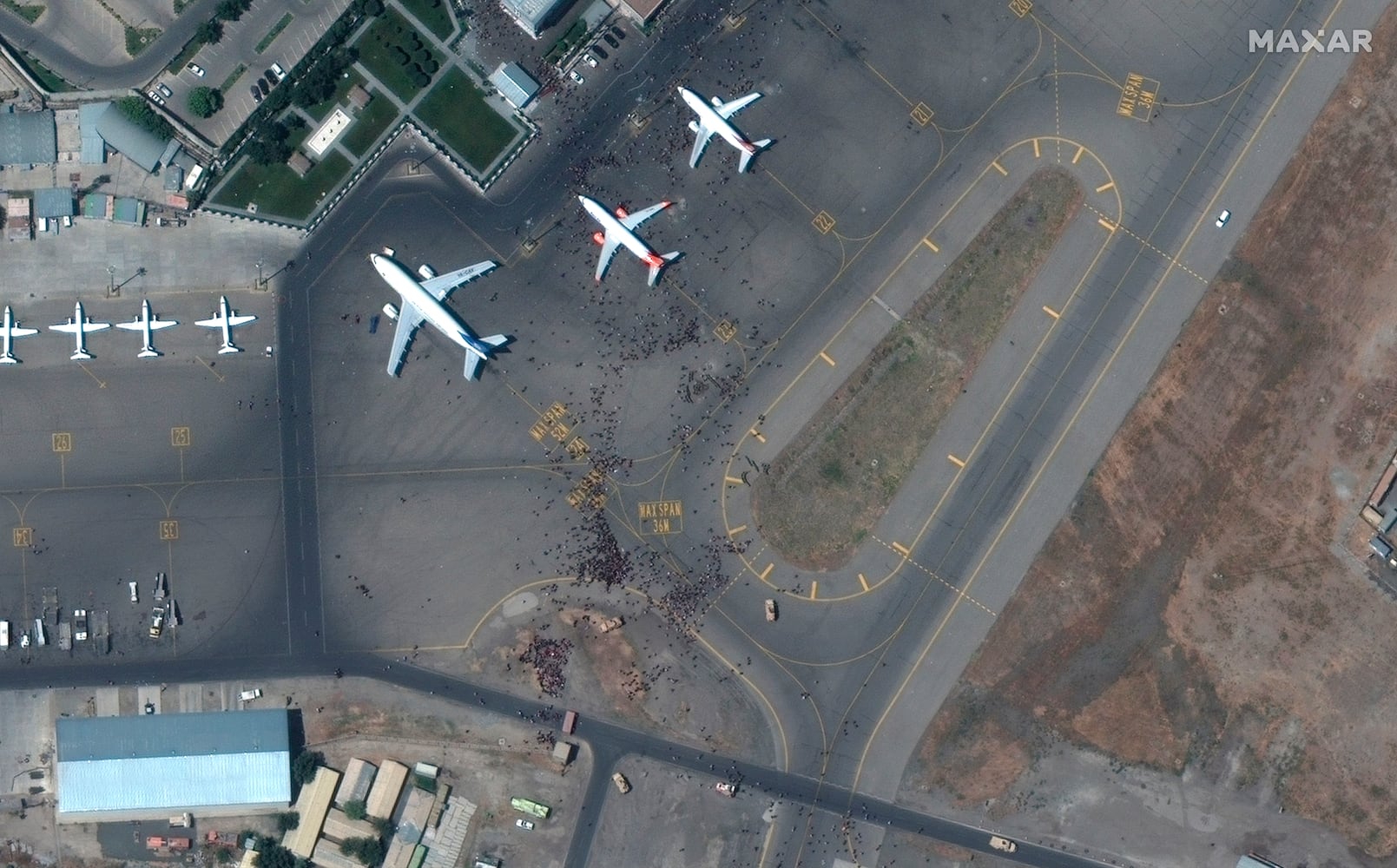 A satellite photo provided by Maxar Technologies shows  people on the tarmac at Kabul’s international airport, also known as Hamid Karzai International Airport in Kabul, Afghanistan on Monday, Aug. 16, 2021. The day after the Afghan president fled and the Taliban installed themselves in the presidential palace, uncertainty reigned and with thousands desperate to flee the country, Kabul’s airport was a scene of chaos. (Satellite image ©2021 Maxar Technologies via The New York Times) -- NO SALES; FOR EDITORIAL USE ONLY WITH NYT STORY AFGHAN TALIBAN FOR AUG. 13, 2021. ALL OTHER USE PROHIBITED. --