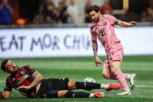 Inter Miami forward Lionel Messi (10) dribbles the ball past Atlanta United defender Derrick Williams, left, during the first half of an MLS soccer match, Sunday, March, 16, 2025, in Atlanta. (AP Photo/Colin Hubbard)