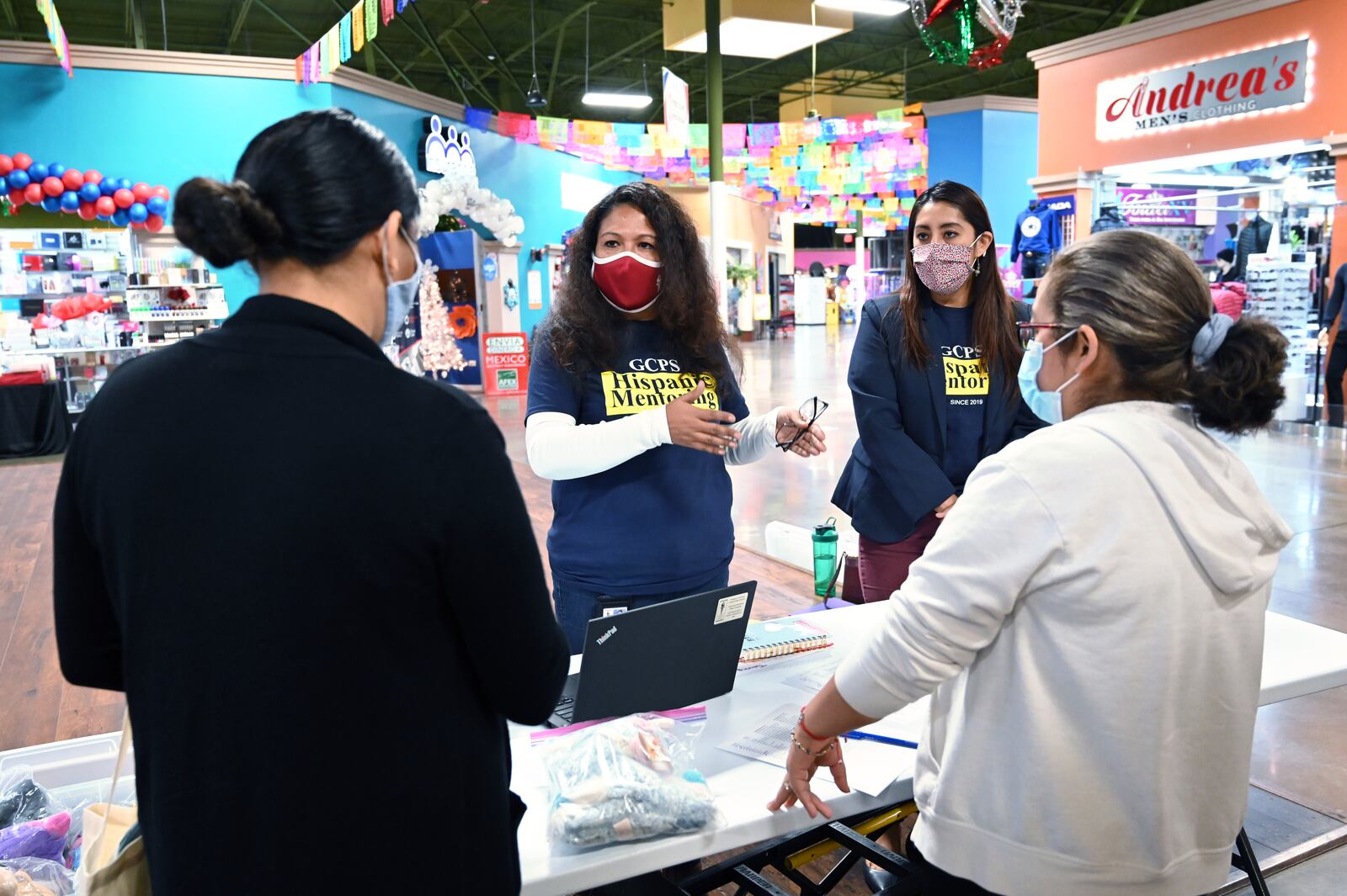 December 9, 2020 Lilburn - Gwinnett County Public Schools' Hispanic Mentoring Program staff Nury Crawford (second from left), program director, and Tania Muniz (third from left) with parent volunteer Marilu Bamaca (right) help parents Maria Alonso (left) as she picks up two science experiments and gift her son at Plaza Las Americas in Lilburn on Wednesday, December 9, 2020. (Hyosub Shin / Hyosub.Shin@ajc.com)