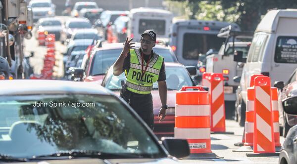 An Atlanta police officer directs traffic outside of Piemont Atlanta Hospital on Wednesday morning, where construction is blocking a lane of Peachtree Road at Collier Road. JOHN SPINK / JSPINK@AJC.COM