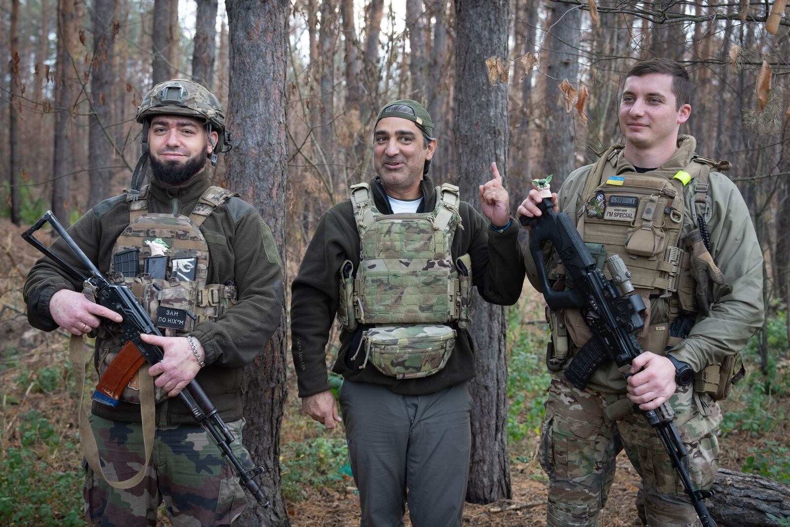 U.S. philanthropist Amed Khan, center, surrounded by Ukrainian servicemen reacts on the sounds of shelling on the frontline in Kharkiv region, Ukraine, Monday, Oct. 28, 2024. (AP Photo/Efrem Lukatsky)