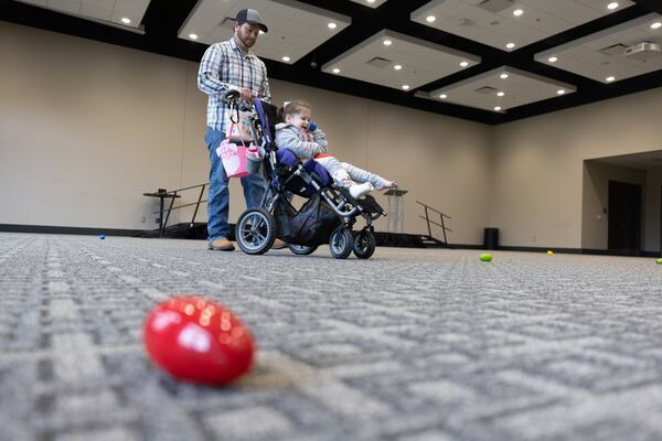 Casey Cook and his daughter Kimberly, six, hunt for beeping eggs during a Beeping Easter egg hunt at Acworth Community Center on Saturday, March 23, 2024. The Cobb County Police Department bomb team puts together the special beeping eggs so they can be found by visually impaired children (Steve Schaefer/steve.schaefer@ajc.com)