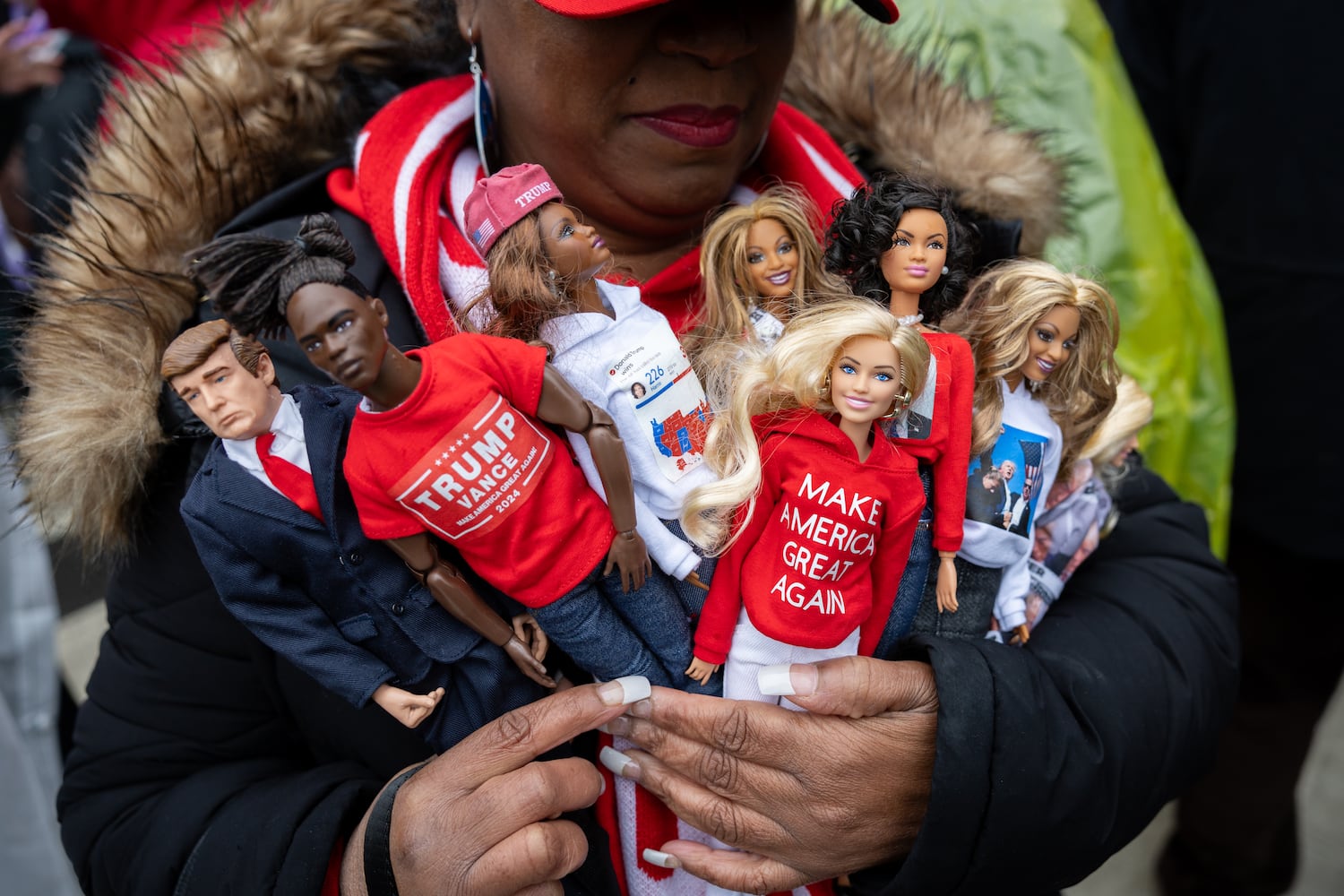 Tabatha Foster of New York holds Barbies with Trump-themed clothes while waiting to enter a Trump rally at Capital One Arena in Washington, D.C. on Sunday, January 19, 2025, one day before Donald Trump’s inauguration. (Arvin Temkar / AJC)