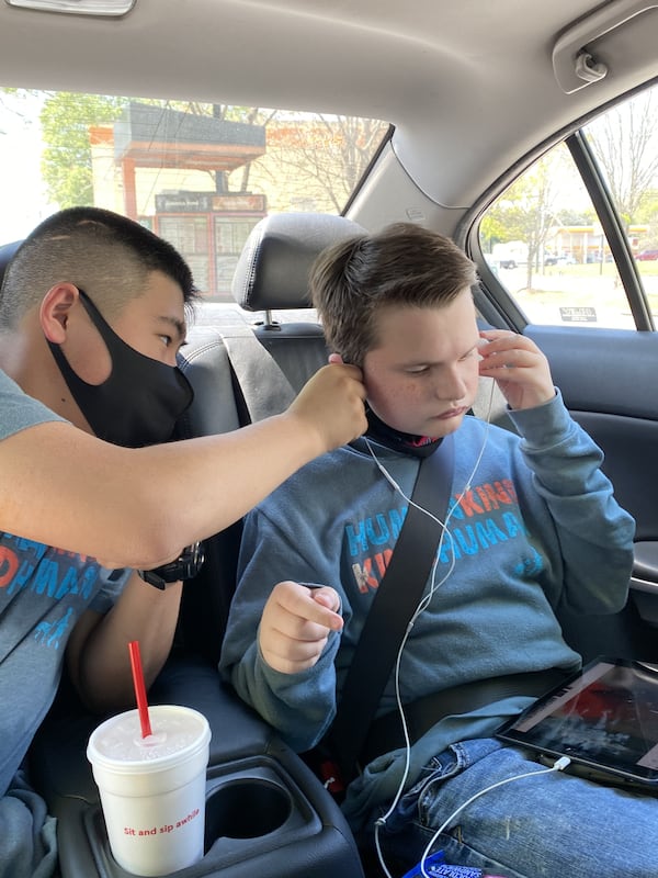 Jun Hayakawa helps his friend, Jonny Hickey, with his ear buds. Courtesy of Linda Hickey