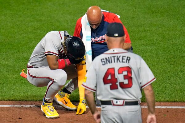 Atlanta Braves' Ronald Acuña Jr., left, is checked by a team trainer and manager Brian Snitker (43) after being hit by a pitch from Pittsburgh Pirates' Colin Holderman during the sixth inning of a baseball game in Pittsburgh, Tuesday, Aug. 8, 2023. (AP Photo/Gene J. Puskar)